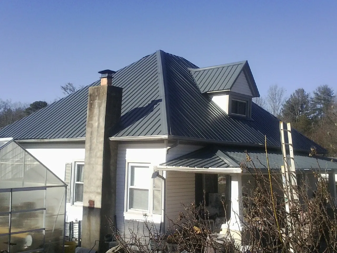Dark blue standing seam metal roof on a white farmhouse with dormer — Slate & Tile Roof Repair by Roofing Brothers in Irwin