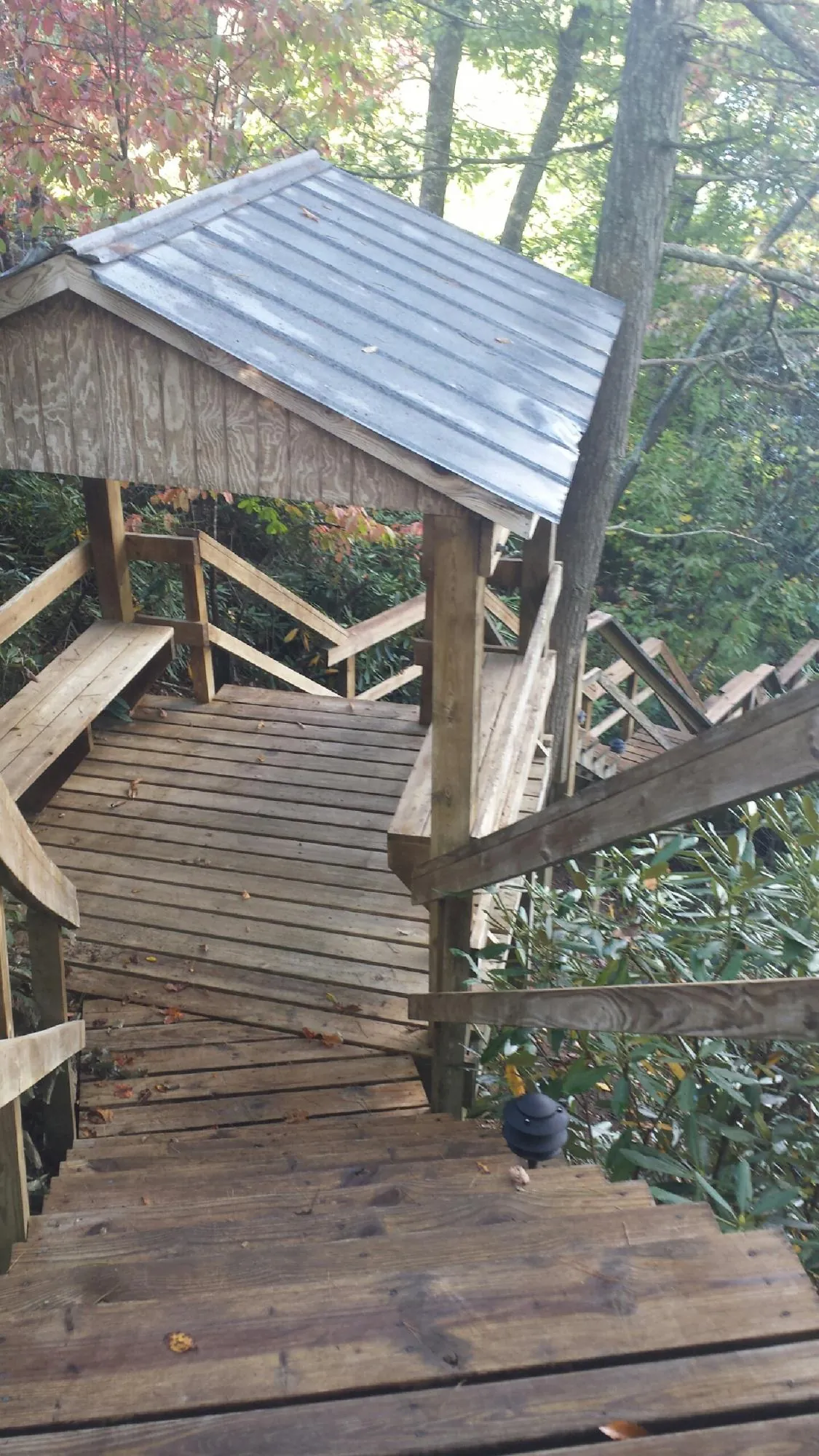 Metal roofed shelter over wooden steps on a wooded walkway — Skylight Repair & Installation work by our crew in Irwin